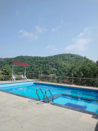 Outdoor swimming pool at Hotel Leopard Valley with Aravalli hill views